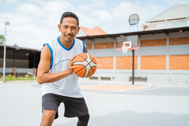 Um jogador de basquete segurando uma bola de basquete com uma pose pronta para driblar a bola