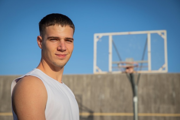 Um jogador de basquete sorridente em uma quadra de basquete com uma cesta atrás dele