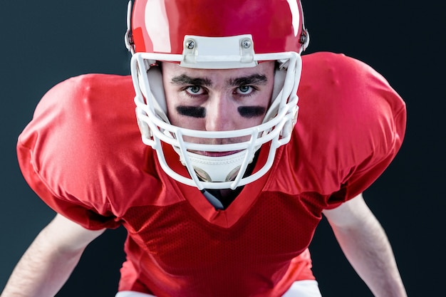 Um jogador de futebol americano sério pegando seu capacete olhando a câmera