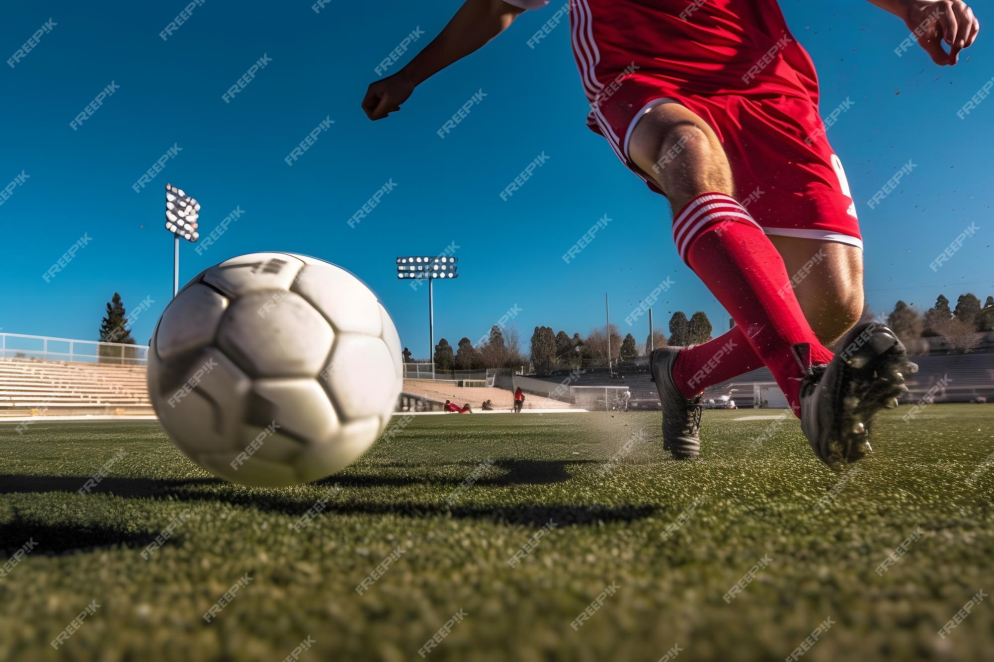 Um jogador de futebol chuta uma bola de futebol em um campo