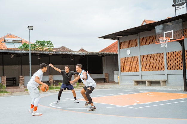 Um jogador driblando a bola vai atacar e dois jogadores adversários ficam no caminho