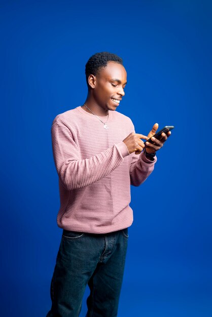 Foto um jovem africano atraente está usando seu smartphone para entrar em contato com amigos