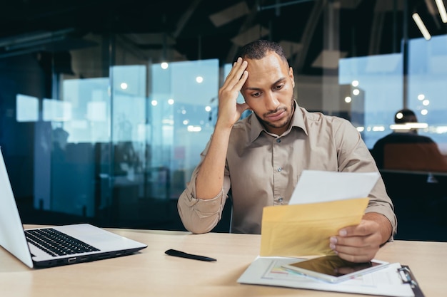 Um jovem afro-americano chateado lê más notícias de uma carta que recebeu, ele está sentado no