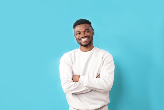 Um jovem afro-americano em uma camiseta branca ri sinceramente em um fundo azul isolado