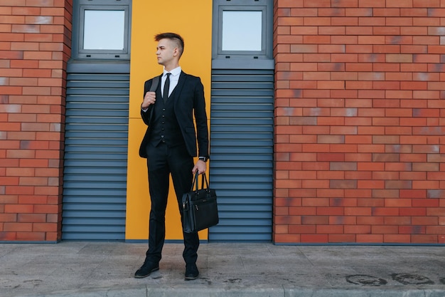 Foto um jovem americano caucasiano vestido com um terno de negócios posa contra o fundo da cidade