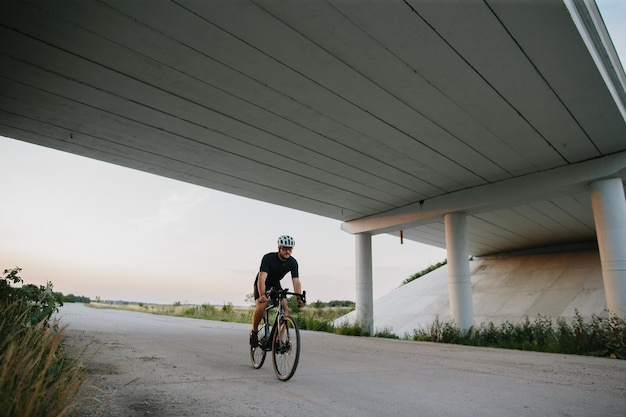 Um jovem anda de bicicleta ao pôr do sol