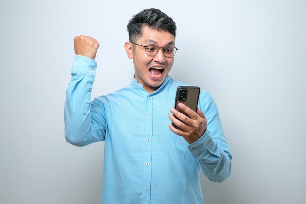 Um jovem asiático chocado usando smartphone para ler boas notícias online