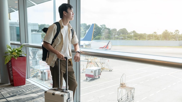 Um jovem asiático com check-in de mala nas férias do aeroporto internacional