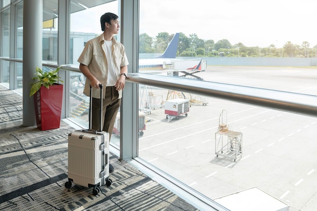 Um jovem asiático com check-in de mala no aeroporto internacional