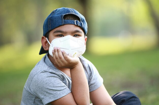 Um jovem asiático de 7 anos usa máscara para proteger contra poeira PM 2.5 e germes
