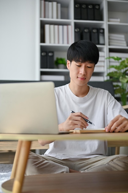Um jovem asiático inteligente e focado está trabalhando em casa gerenciando seu trabalho