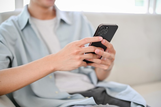 Um jovem asiático usando seu smartphone no sofá da sala de estar