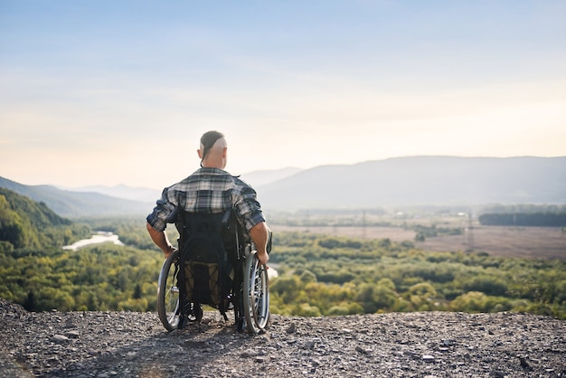 Um jovem atleta está temporariamente incapacitado em uma cadeira de rodas, aproveitando o ar puro das montanhas.