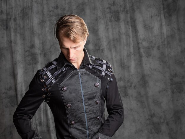 Um jovem atraente em uma camisola de fantasia posando no estúdio em um fundo de tecido cinza