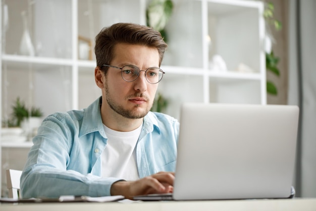 Um jovem atraente está trabalhando em um laptop