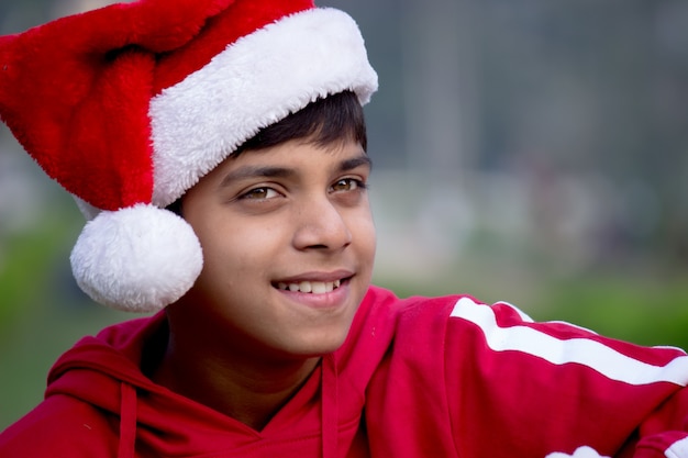 Um jovem atraente sorridente adolescente feliz no chapéu do Papai Noel, olhando para longe