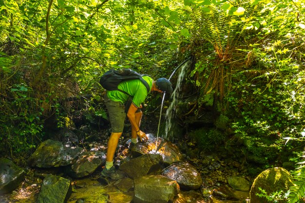 Um jovem bebendo água de uma fonte natural em monte igueldo, guipuzcoa,