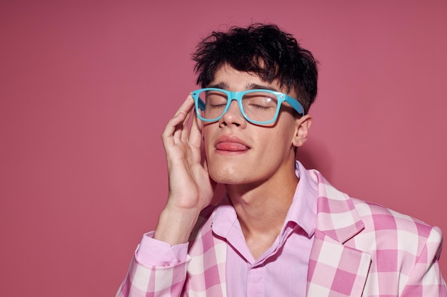 Um jovem blazer rosa de óculos na moda posando fundo rosa de estúdio inalterado