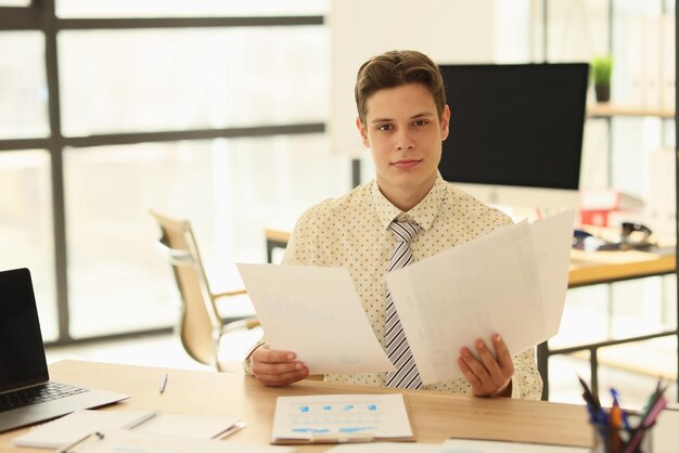 Um jovem bonito assistindo documento no escritório fechando o local de trabalho do empresário