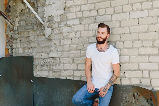 Um jovem bonito com barba em um interior de estilo grunge