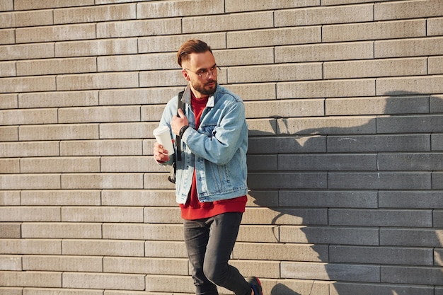 Um jovem bonito em roupas casuais está ao ar livre no dia ensolarado