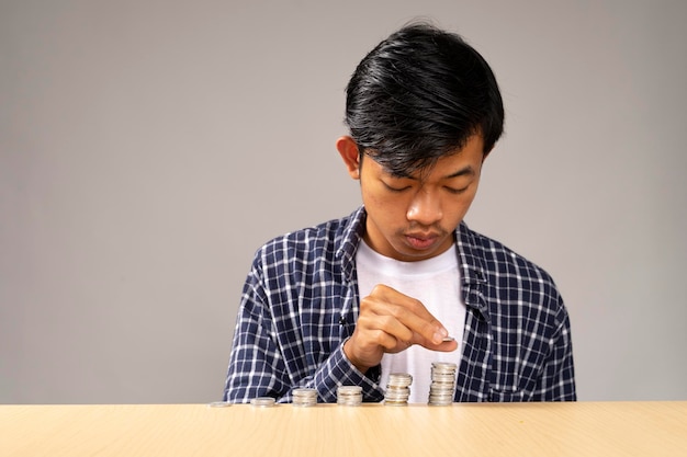 Um jovem bonito está organizando as moedas que recebeu conceito de poupança