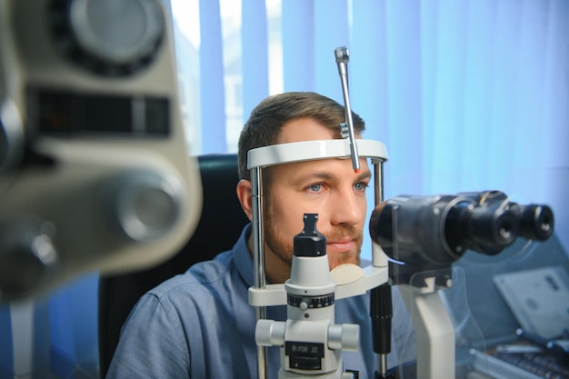 Um jovem bonito está verificando a visão ocular na clínica de oftalmologia moderna Paciente na clínica de oftalmologia