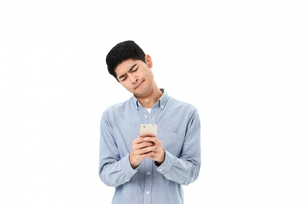 Um jovem bonito, satisfeito com uma camisa azul com telefone