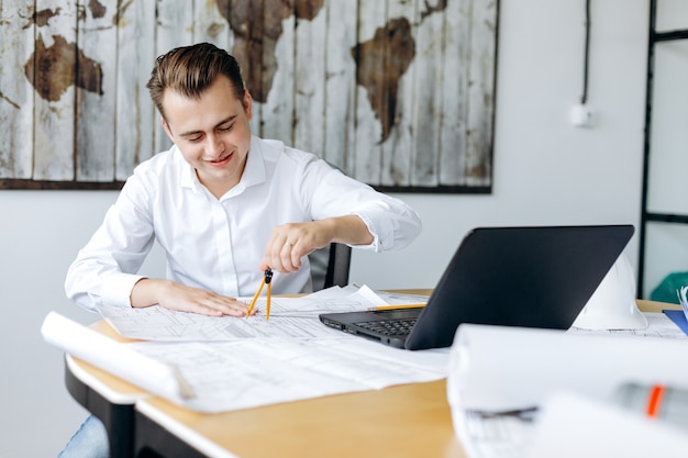 Um jovem bonito trabalhando feliz em um desenho em seu escritório