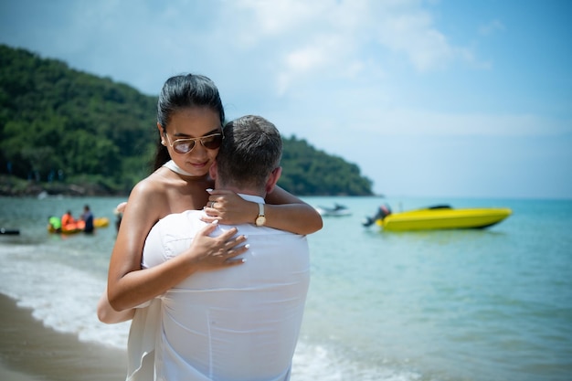 Um jovem branco a pedir em casamento a uma asiática com um anel de diamantes numa praia.