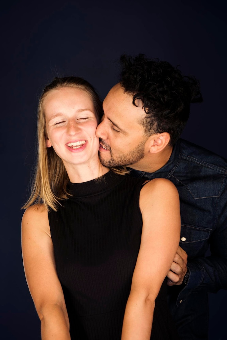 Foto um jovem casal a beijar-se contra um fundo preto.