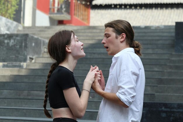 Um jovem casal a dançar no parque e a beijar-se felizes juntos.