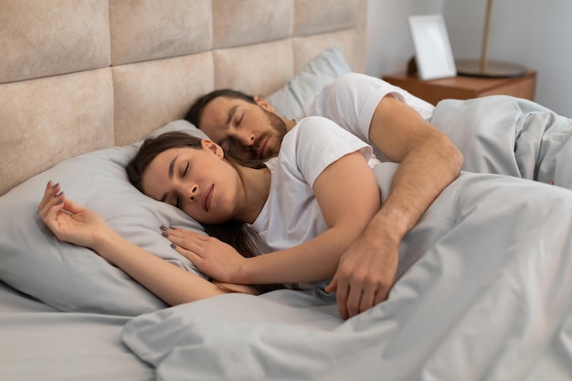 Um jovem casal a dormir juntos numa cama confortável.