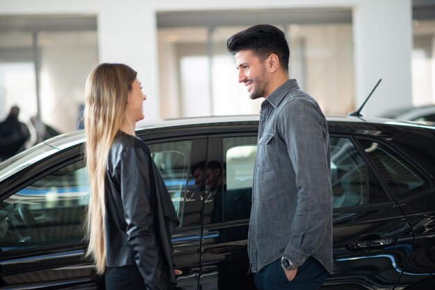 Um jovem casal a escolher um carro novo para comprar na loja de concessionários