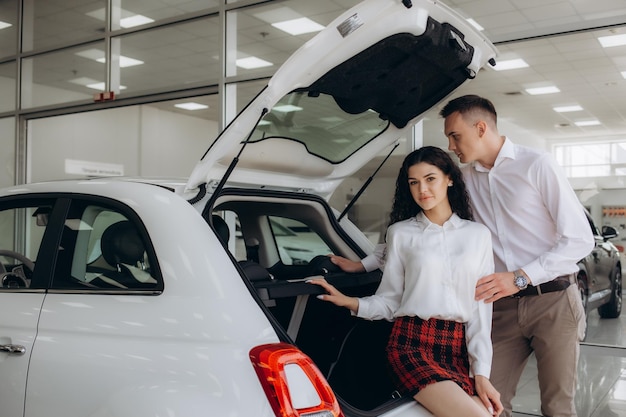 Um jovem casal a escolher um carro novo para comprar na loja de concessionários