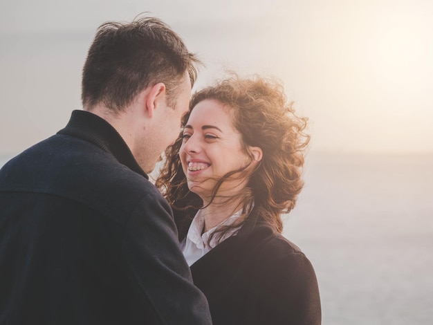 Um jovem casal a namorar ao pé do mar contra o céu.