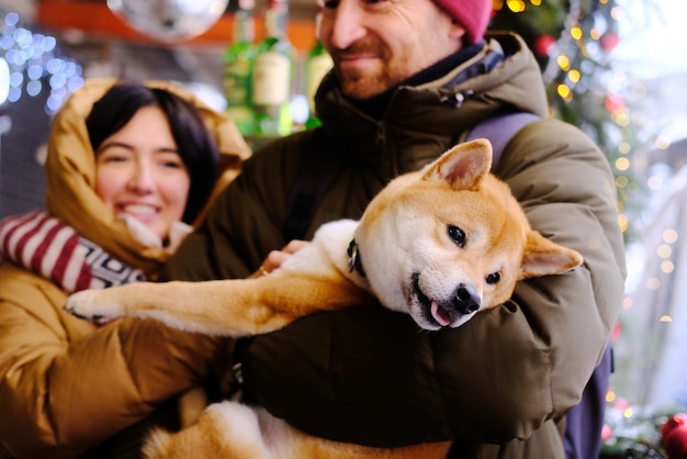 Um jovem casal abraça sua cachorrinha ruiva Akita Inu