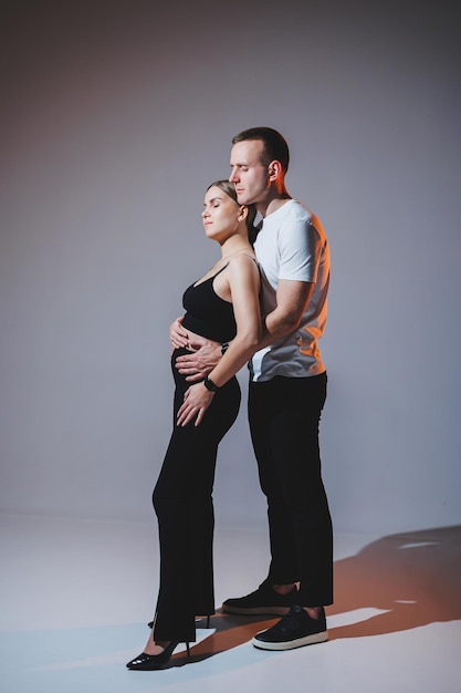 Um jovem casal alegre e feliz se abraçando em um fundo liso Um homem estiloso e uma mulher apaixonada estão se abraçando com ternura
