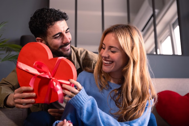 Foto um jovem casal amoroso com uma caixa de presentes em forma de coração para a celebração do dia dos namorados.