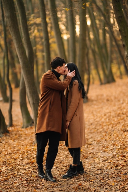 Um jovem casal apaixonado a caminhar no parque num dia de outono a desfrutar do tempo juntos.