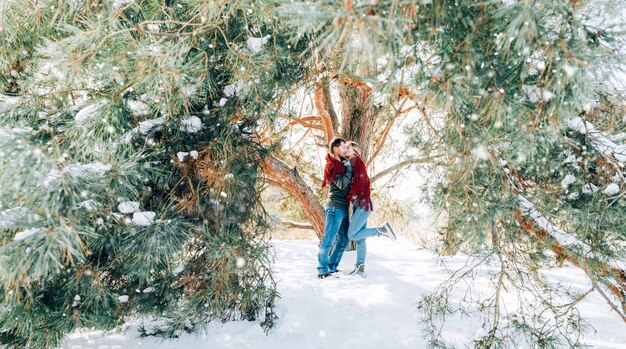 Um jovem casal apaixonado está descansando nas montanhas em uma floresta coberta de neve. conceito de descanso articular