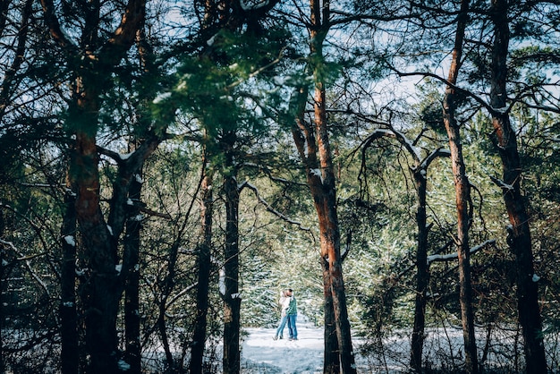 Um jovem casal apaixonado está descansando nas montanhas em uma floresta coberta de neve. conceito de descanso articular