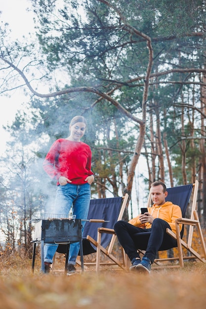 Um jovem casal apaixonado está grelhando um churrasco na natureza Recreação familiar na natureza