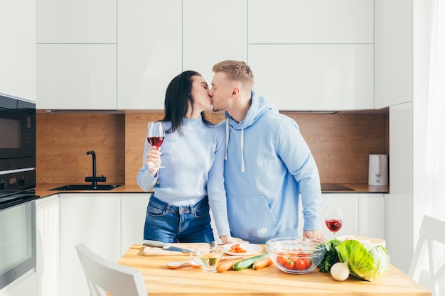 Um jovem casal apaixonado, um homem e uma mulher, estão cozinhando o jantar juntos e se divertindo em um novo apartamento