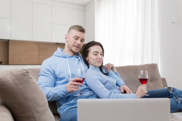Um jovem casal apaixonado, um homem e uma mulher relaxando no sofá e olhando para um laptop