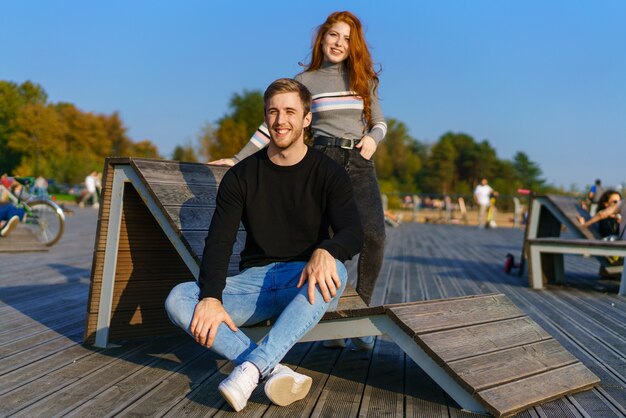 Um jovem casal apaixonado um homem e uma mulher se abraçam em um banco na área de lazer um lindo redha ...