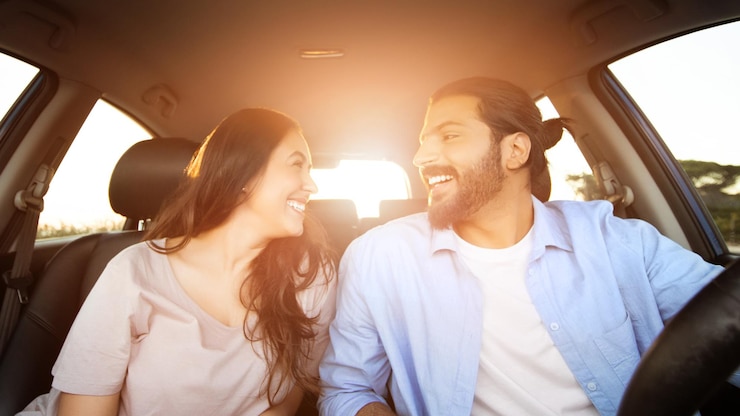 Foto um jovem casal árabe a rir-se a desfrutar de um passeio de carro.