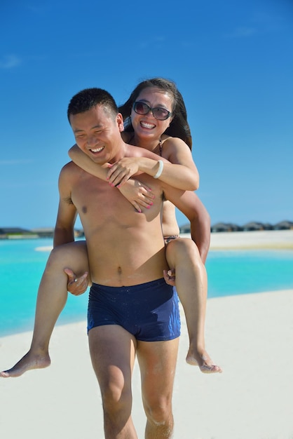 Um jovem casal asiático feliz se diverte e passa um tempo romântico no verão em uma bela praia de areia branca.