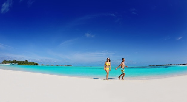 Um jovem casal asiático feliz se diverte e passa um tempo romântico no verão em uma bela praia de areia branca.