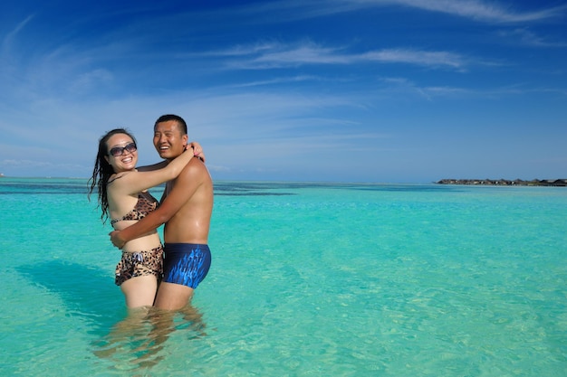 Um jovem casal asiático feliz se diverte e passa um tempo romântico no verão em uma bela praia de areia branca.